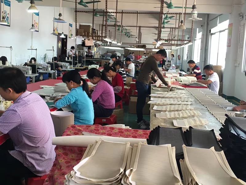 Large handbag production workshop with workers assembling bag panels on long assembly lines