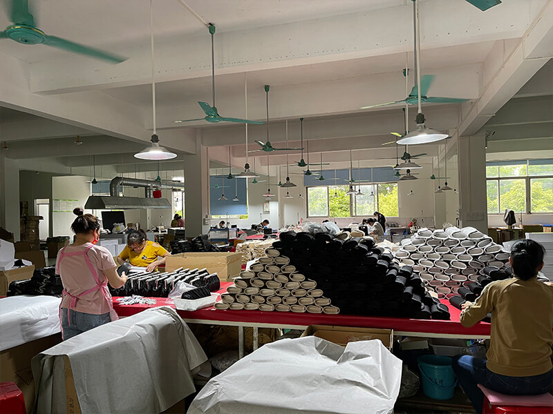 Production department of NaChi leather factory with workers assembling handbags on worktables